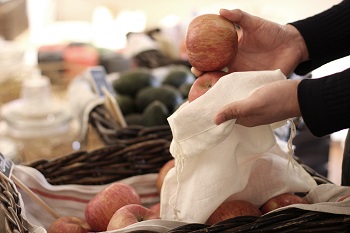 A customer is placing an apple into a pouch instead of using a plastic bag.Photo provided by The Picker.